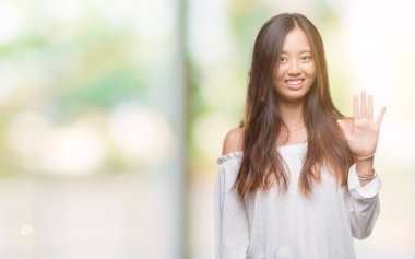 Genç Asyalı kadın gösterilen ve parmakları ile işaret izole arka plan üzerinde beş kendinden emin ve mutlu gülümseyerek iken numara.