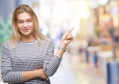 Kameraya bakarak yan el ve parmak ile işaret izole arka yüzünde kocaman bir gülümseme ile genç beyaz kadın.