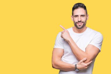 Yakışıklı adam izole sarı üzerinde beyaz t-shirt giyen işaretçi el parmak reklam, ciddi ve sakin yüz gösterilen yan için arka plan