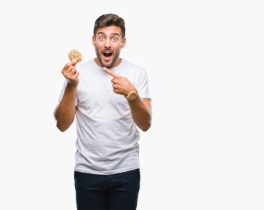Yakışıklı delikanlı izole arka el ve parmak ile işaret çok mutlu üzerinde çikolata çerez yemek