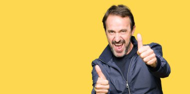 Onaylama ceket giyen orta yaş yakışıklı adam el ile pozitif jest yapıyor gülümseyen ve başarı için mutlu yaşasın. Kamera, kazanan jest arıyorsunuz.