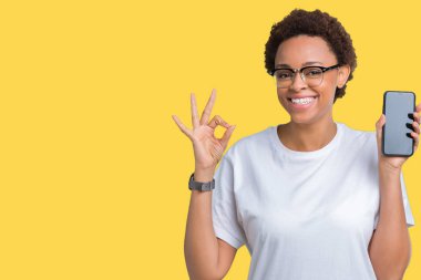 Genç Afro-Amerikan kadın gösteren smartphone ekran parmak, mükemmel sembolü ile ok işareti yapıyor izole arka plan üzerinde