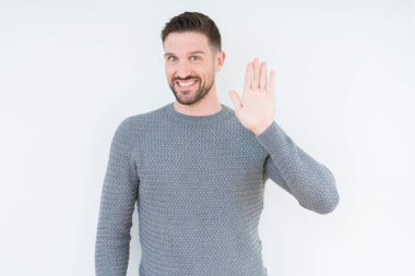 Yakışıklı delikanlı izole arka plan Waiving mutlu selam söyleyerek üzerinde rahat kazak ve gülümseyen, dostça karşılama jest