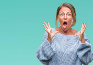 Üzerinde kış kazak giyen orta yaş üst düzey İspanyol kadın deli kutluyor arka plan izole ve başarı için kaldırdı kollarını açarak hayrete ve heyecanlı çığlık gözleri açık. Kazanan kavramı