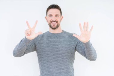 Gösterilen ve parmakları ile işaret izole arka plan üzerinde rahat kazak giyen genç yakışıklı adam kendinden emin ve mutlu gülümseyerek süre sekiz numara.
