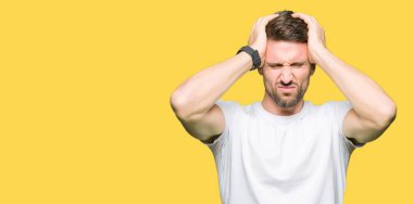 Yakışıklı adam çünkü umutsuz ve stresli baş ağrısı acı casual beyaz t-shirt giyen ağrı ve migren. Ellerini kafasına.