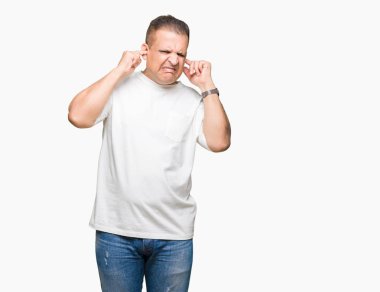 Orta yaş Arap adam wearig t-shirt kulakları ile yüksek sesle müzik gürültü rahatsız ifade parmaklarıyla kapsayan izole arka plan üzerinde beyaz. Sağır kavramı.