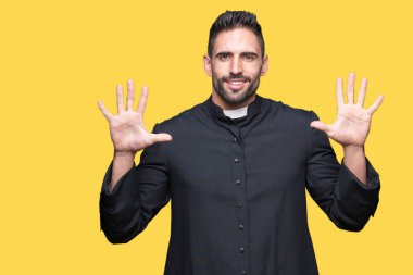 Genç Hıristiyan rahip gösterilen ve parmakları ile işaret izole arka plan üzerinde kendinden emin ve mutlu gülümseyerek süre on numara.