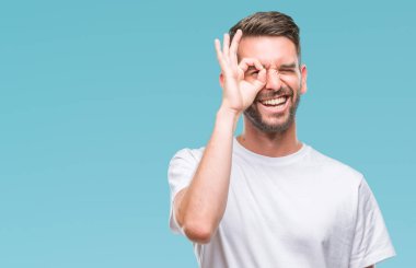 Genç yakışıklı adam gülümsüyor, parmakları ile mutlu yüz üzerinden seyir göz el ile ok jest yapıyor izole arka plan üzerinde.