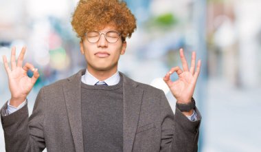 Genç yakışıklı iş adamı ile gözlüklü afro rahatla ve gülümseyen gözlerle kapalı parmak jestle meditasyon yapıyor. Yoga kavramı.