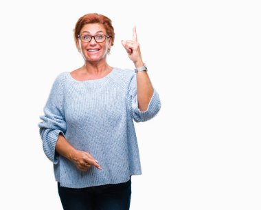 Başarılı fikirle izole arka plan işaret parmağı üzerinde gözlük takan Atrractive üst düzey beyaz Kızıl saçlı kadın. Çıktıktan ve mutlu. Bir numara.