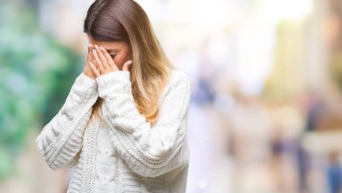 Genç güzel kadın ağlayarak süre elleriyle yüzünü kapsayan üzgün ifade ile izole arka plan üzerinde rahat beyaz kazak. Depresyon kavramı.