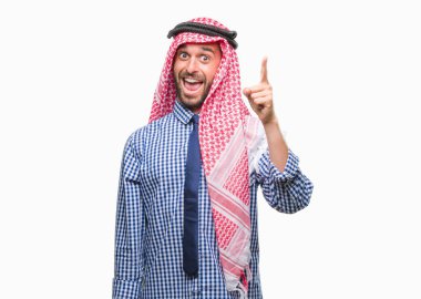 Başarılı fikirle izole arka plan işaret parmağı üzerinde keffiyeh giyen genç yakışıklı Arap iş adam. Çıktıktan ve mutlu. Bir numara.