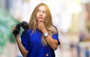 Genç güzel sarışın kadın izole arka plan ciddi bir yüz düşünme hakkında soru, çok karışık bir fikir üzerinde dürbün ile seyir
