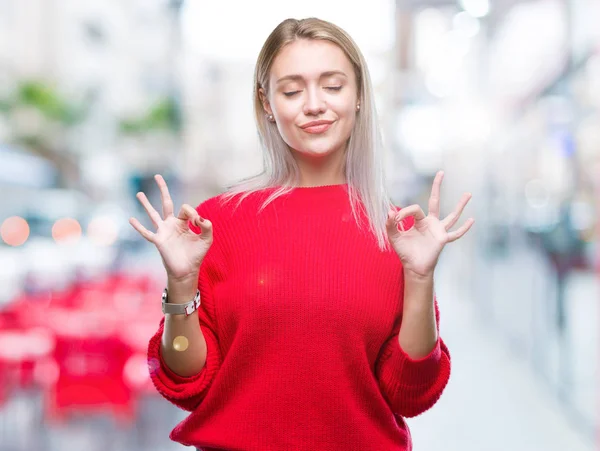 Sarışın genç kadın giyiyor kış kazak izole arka plan üzerinde dinlenmek ve gülümseyen gözlerle kapalı parmak jestle meditasyon yapıyor. Yoga kavramı.
