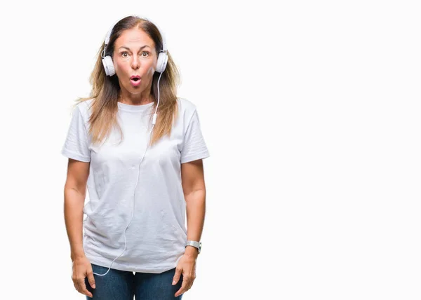 中年西班牙妇女听音乐戴耳机在孤立的背景害怕和震惊与惊喜的表情 恐惧和兴奋的脸 — 图库照片