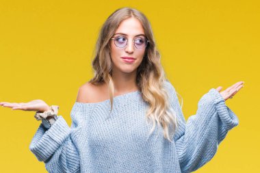 Güzel genç sarışın kadın üzerinde güneş gözlüğü takıyor arka plan clueless ve şaşkın bir ifadeyle kollar ve eller kaldırdı izole. Şüphe kavramı.