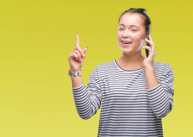 Genç güzel beyaz kadın Smartphone'da izole arka plan üzerinde bir fikir veya parmakla gülen yüz, bir numara ile soru ile sürpriz söz