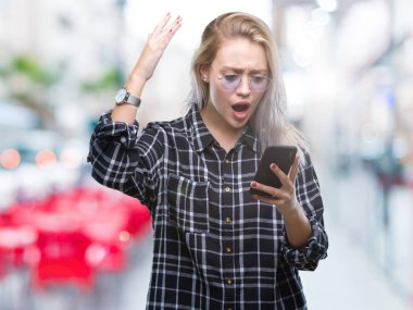 Sarışın genç kadın manifatura öfke, çılgın ve yükseltilmiş el, öfke kavramı ile diye bağıran ile smartphone üzerinde izole arka rahatsız ve sinirli bağırarak kullanarak ileti gönderme