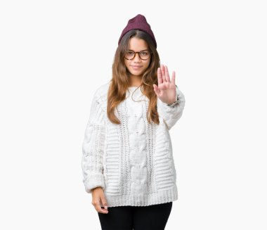 Kış şapka ve gözlük stop yapıyor izole arka plan üzerinde giyen genç güzel esmer hipster kadın elin avuç ile şarkı. Negatif ve ciddi bir jest yüz ifadesiyle uyarı.