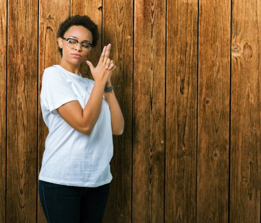 Güzel genç Afro-Amerikan kadın el hareketi ile sembolik silah tutan, çekim silah, kızgın yüz öldürmek oynamaya izole arka plan üzerinde gözlük