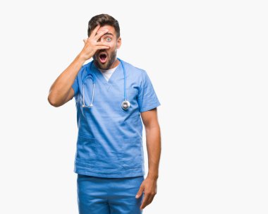 Mahcup ifadeyle parmaklarımın arasından görünen yüz ve gözler el ile kapsayan şok izole arka plan bakmak üzerinde genç yakışıklı Doktor cerrah adam.