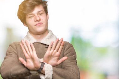 Yakışıklı delikanlı izole arka plan ret ifade geçiş silah ve avuç içi eksi işareti, kızgın surat yapıyor üzerinde kış palto giyiyor