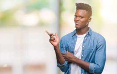 Kameraya bakarak yan el ve parmak ile işaret eden genç Afro-Amerikan adam yüzünde kocaman bir gülümseme ile izole arka plan üzerinde.