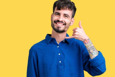 Yakışıklı delikanlı yapıyor gülümseyen izole arka plan üzerinde telefon hareketi ile el ve parmak telefonda konuşuyor gibi. Kavramları iletişim.