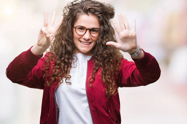 Ceket ve gözlük gösterilen ve parmakları ile işaret izole arka plan üzerinde giyen güzel esmer kıvırcık saçlı Genç kız kendinden emin ve mutlu gülümseyerek süre sekiz numara.