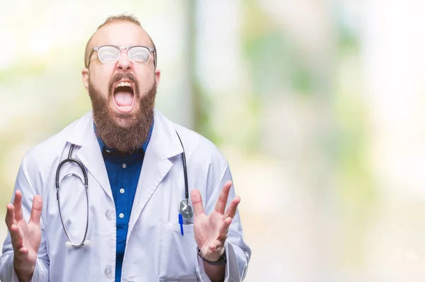 年轻的高加索医生男子穿着医疗白色外套在孤立的背景疯狂和疯狂的喊声和大喊大叫与积极的表情和武器提出 挫折的概念 — 图库照片