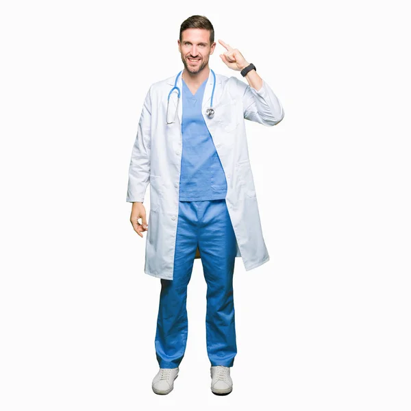 英俊的医生穿医疗制服在孤立的背景微笑用一个手指指向头部 伟大的想法或想法 良好的记忆力 — 图库照片