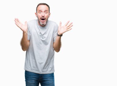 Orta yaş üst düzey ağarmış adam izole arka plan clueless ve şaşkın bir ifadeyle kollar ve eller kaldırdı. Şüphe kavramı.