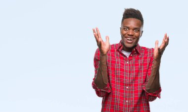 Afrikalı-Amerikalı genç deli kutluyor ve silah ile başarı için heyecanlı çığlık kaldırdı ve açık gözleri hayret izole arka plan üzerinde. Kazanan kavramı