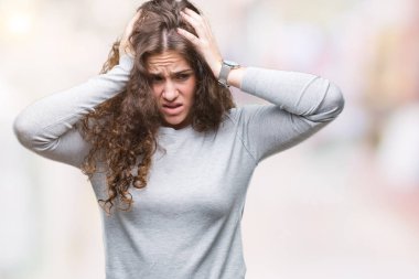 Güzel esmer kıvırcık saçlı Genç kız bir kazak giyiyor çünkü umutsuz ve stresli baş ağrısı acı izole arka plan üzerinde ağrı ve migren. Ellerini kafasına.