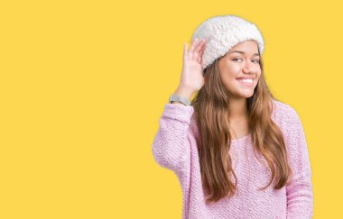 Bir işitme söylenti ya da dedikodu için dinleme kulak üzerinde el ile gülümseyen izole arka plan üzerinde kazak ve kış şapka giyen genç güzel esmer kadın. Sağırlık kavramı.