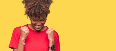 Gülümseyen ve başarı için çığlık güzel genç Afro-Amerikan kadın izole arka plan çok mutlu ve heyecanlı kaldırdı, silah ile kazanan jest yapıyor. Kutlama kavramı.