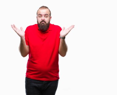 Üzerinde kırmızı gömlek giyen genç beyaz hipster adam arka plan clueless ve şaşkın bir ifadeyle kollar ve eller kaldırdı izole. Şüphe kavramı.