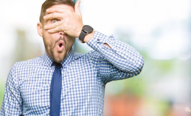 Yüz ve gözler el ile kapsayan şok kravat bakmak giymiş yakışıklı iş adamı mahcup ifadeyle parmaklarımın arasından arıyorsunuz.