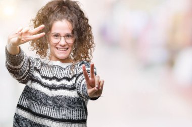 Güzel esmer kıvırcık saçlı Genç kız zafer işareti yapıyor parmak gösterilen kamera seyir gülümseyen izole arka plan üzerinde gözlük takıyorum. İki numaralı.