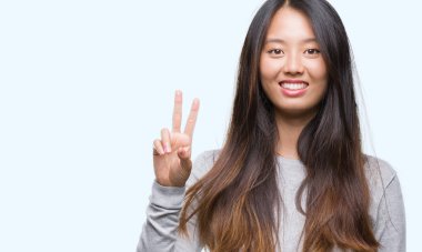 Genç Asyalı kadın mutlu yüz zafer işareti yaparken kameraya göz kırpıyor ile gülümseyen izole arka plan üzerinde. İki numaralı.