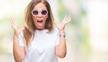 Orta yaş İspanyol kadın üzerinde moda güneş gözlüğü takıyor deli kutluyor arka plan izole ve silah ile başarı için yükseltilmiş ve açık gözleri heyecanlı çığlık hayrete düşürdü. Kazanan kavramı