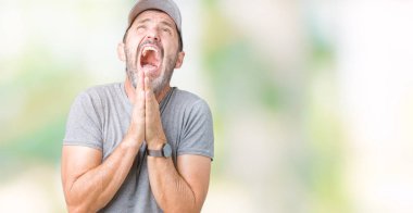 Yalvarıyor ve umut ifade yüzünde çok duygusal ve endişe ile birlikte elleriyle dua izole arka plan üzerinde spor şapkası yakışıklı orta yaş ağarmış komuta sizde. Bağışlanmak. Din kavramı.