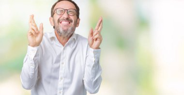 Umut ve gözleri kapalı geçiş parmaklarıyla gülümseyen izole arka plan üzerinde gözlük takan yakışıklı orta yaş zarif üst düzey iş adamı. Şans ve batıl kavramı.