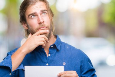 Boş kağıt ciddi bir yüz düşünme hakkında soru, çok karışık fikir tutan izole arka plan üzerinde uzun saçlı yakışıklı delikanlı