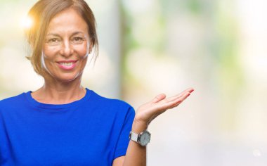 Orta yaş neşeli sunulması ve kameraya bakarak avucunun ile işaret gülümseyen izole arka plan üzerine İspanyol kadın kıdemli.