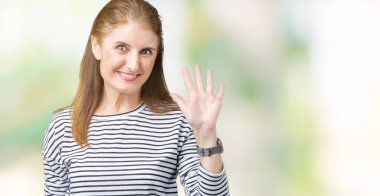 Çizgili kış kazak izole arka plan Waiving mutlu selam söyleyerek üzerinde ve gülümseyen, dostça karşılama jest giyen orta yaş olgun güzel kadın