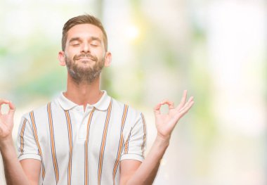 Yakışıklı delikanlı izole arka plan üzerinde dinlenmek ve gülümseyen gözlerle parmak ile meditasyon jest yapıyor kapalı. Yoga kavramı.