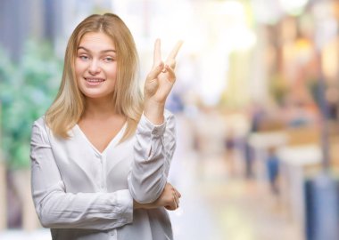 Mutlu yüz zafer işareti yaparken kameraya göz kırpıyor ile gülümseyen izole arka plan üzerinde beyaz kadın. İki numaralı.