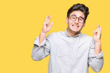 Umut ve gözleri kapalı geçiş parmaklarıyla gülümseyen izole arka plan üzerinde gözlük takan yakışıklı delikanlı. Şans ve batıl kavramı.